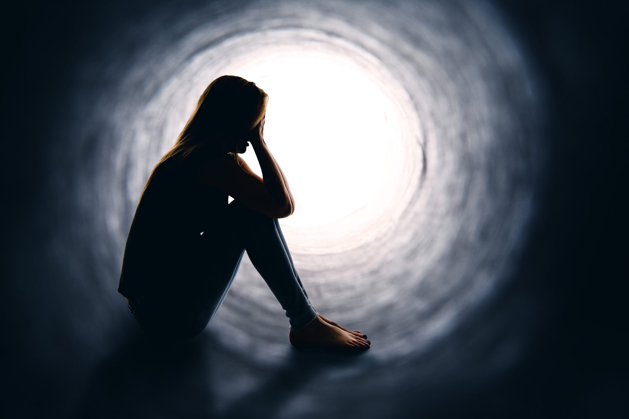 Woman in a tunnel sitting down upset.